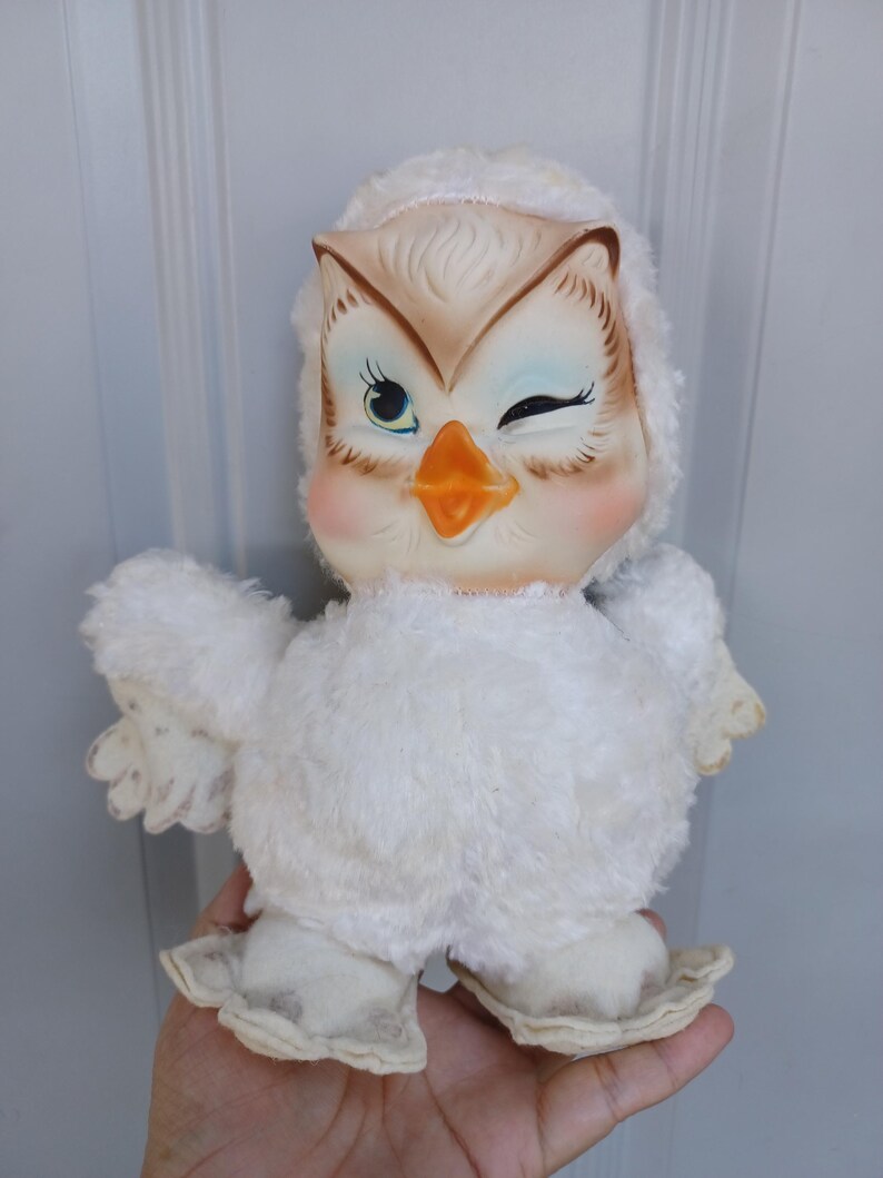 Puede incluir: Juguete vintage de b&uacute;ho de peluche blanco con un gui&ntilde;o. El b&uacute;ho tiene una cabeza color crema con detalles marrones y azules, un pico naranja y mejillas rosadas. El cuerpo est&aacute; cubierto de material de felpa blanco y suave.