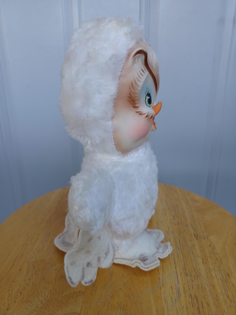 Puede incluir: Figura de b&uacute;ho de peluche blanco vintage con capucha. El b&uacute;ho tiene una cara pintada con ojos azules, un pico color melocot&oacute;n y mejillas rosadas. El b&uacute;ho est&aacute; sobre una superficie de madera.