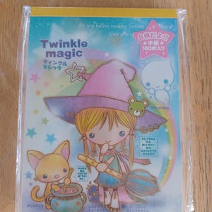 May include: A rectangular notepad titled Twinkle Magic featuring a cartoon character in a purple witch hat holding a broomstick, a small cat stirring a pot, and a ghost. The cover has a rainbow background with stars and Japanese text.