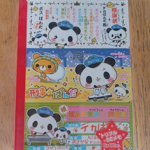 May include: A rectangular notepad featuring three horizontal sections with cartoon panda police illustrations. The top section is white, the middle is yellow, and the bottom is green. Each section contains Japanese text, panda characters in blue police hats, and a red star-shaped sticker on the bottom right.