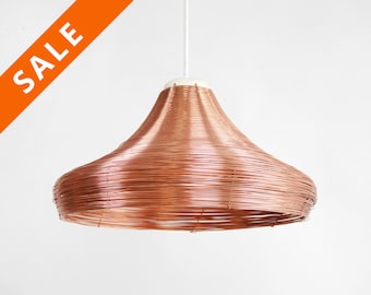 May include: A copper wire pendant light fixture with a bell-shaped shade. The shade is made of many layers of copper wire, creating a unique and modern look.