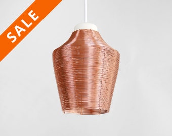May include: A copper wire pendant light with a white ceiling mount. The light fixture is shaped like a vase and has a smooth, shiny finish.