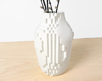 May include: White ceramic vase with a geometric, pixelated design. The vase is shaped like a traditional vase with a round body and a narrow neck.