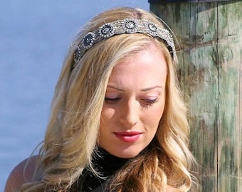 May include: A woman with long blonde hair wearing a silver headband with decorative embellishments. The headband is made of metal and has a beaded design.