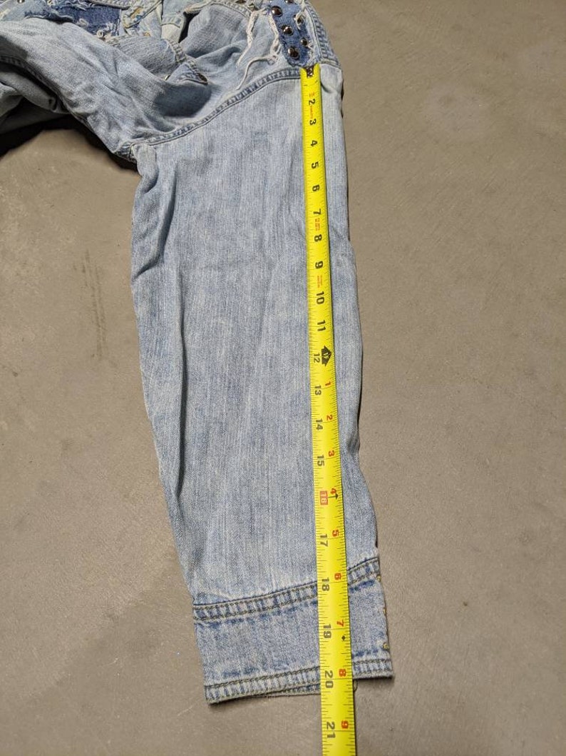 May include: Light blue denim jacket with a frayed hem and a yellow measuring tape showing the length of the sleeve is 50.8 cm.