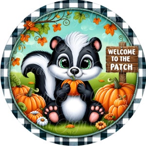 May include: A round, decorative sign featuring a cartoon skunk holding a pumpkin, surrounded by pumpkins and fall foliage. The sign reads "WELCOME TO THE PATCH" on a wooden sign. The border is a black and white checkered pattern.