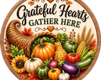 May include: A round wooden-framed sign featuring the text Grateful Hearts GATHER HERE in black and green script. The design includes a woven cornucopia overflowing with pumpkins, gourds, corn, a sunflower, an eggplant, and garlic, accented by autumn leaves.