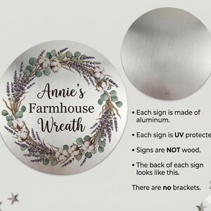 Puede incluir: Un letrero circular de aluminio con una corona impresa de ramas de lavanda, hojas de eucalipto y flores de algod&oacute;n. El texto central dice Annie's Farmhouse Wreath. Un segundo c&iacute;rculo m&aacute;s peque&ntilde;o muestra el reverso de metal cepillado.