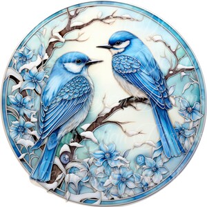 K&ouml;nnte beinhalten: Ein rundes Kunstwerk im Stil eines Glasfensters mit zwei blauen V&ouml;geln auf einem schneebedeckten Ast. Die V&ouml;gel haben wei&szlig;e Akzente und sind von blauen Blumen und einem hellblauen Hintergrund umgeben. Das Kunstwerk ist mit einem blauen Rand versehen.