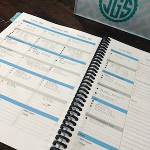 May include: A weekly planner with a black spiral binding. The planner has a blue and white cover with the days of the week listed across the top. The planner is open to Friday, August 17th, and the page has a list of tasks for the day, including "vocab read exercises", "final essay", and "make model timeline".