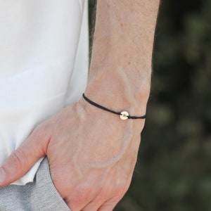 Peut inclure: Un bracelet en cordon noir avec un petit charme en or. Le charme a un design simple.