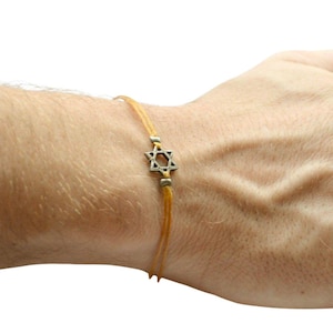 May include: A yellow string bracelet with a silver Star of David charm.