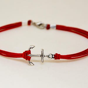 May include: A red cord bracelet with a silver anchor charm.