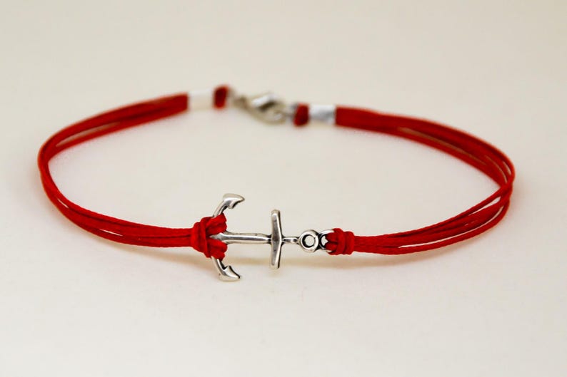 May include: A red cord bracelet with a silver anchor charm.
