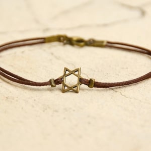 May include: A brown cord bracelet with a gold-toned Star of David charm.