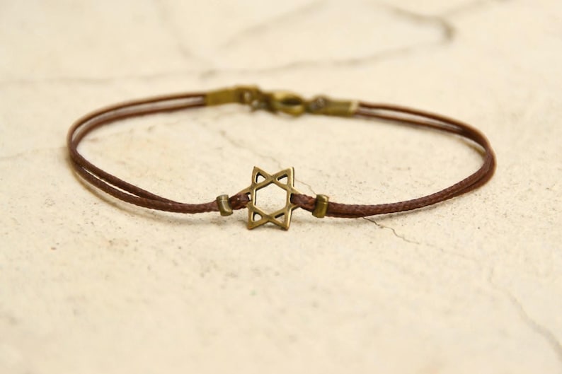 May include: A brown cord bracelet with a gold-toned Star of David charm.