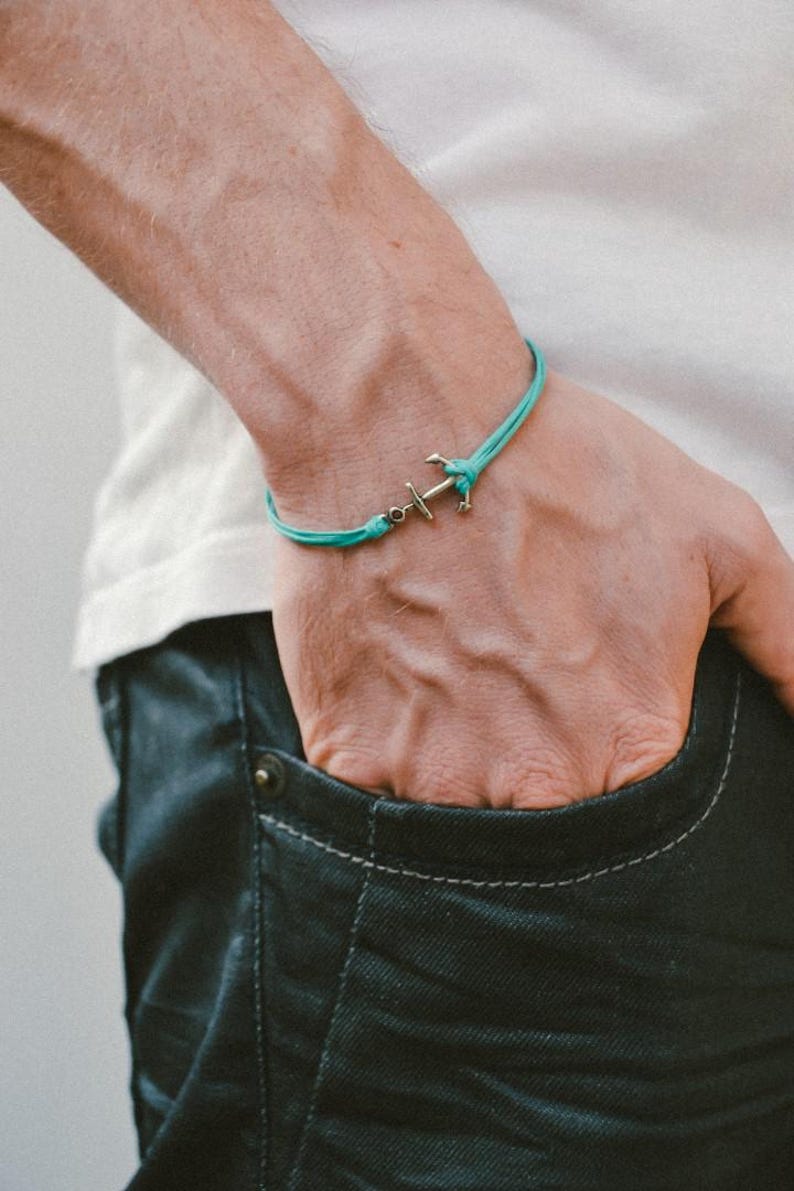 May include: A turquoise blue cord bracelet with a silver anchor charm.