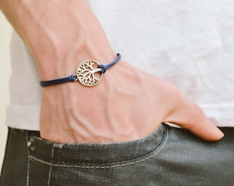 May include: A blue cord bracelet with a silver tree of life charm.