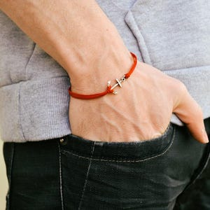 May include: A red string bracelet with a silver anchor charm.