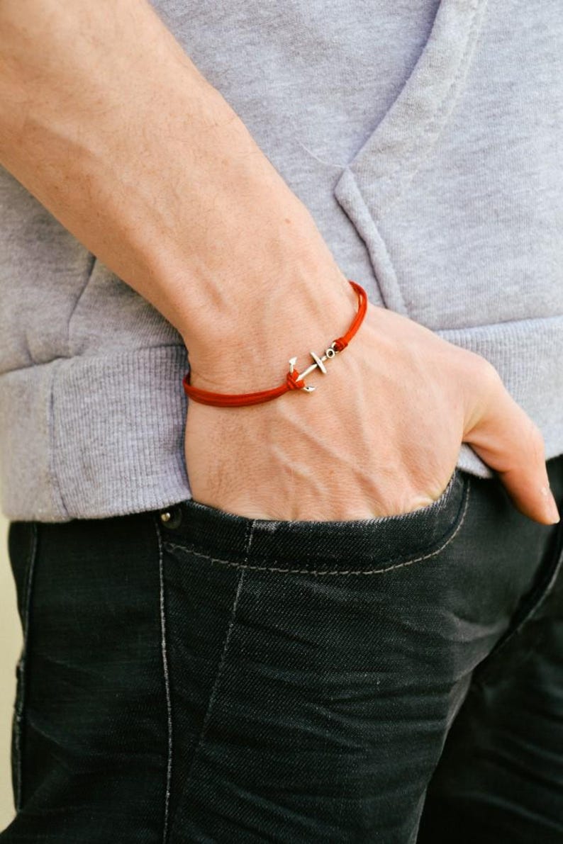 May include: A red string bracelet with a silver anchor charm.