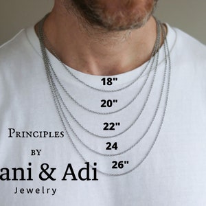 Puede incluir: Un collar de cadena de plata en cinco longitudes diferentes: 46 cm, 51 cm, 56 cm, 61 cm y 66 cm. El collar se muestra en el cuello de una persona.