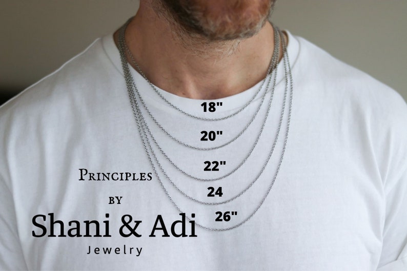 Puede incluir: Un collar de cadena de plata en cinco longitudes diferentes: 46 cm, 51 cm, 56 cm, 61 cm y 66 cm. El collar se muestra en el cuello de una persona.