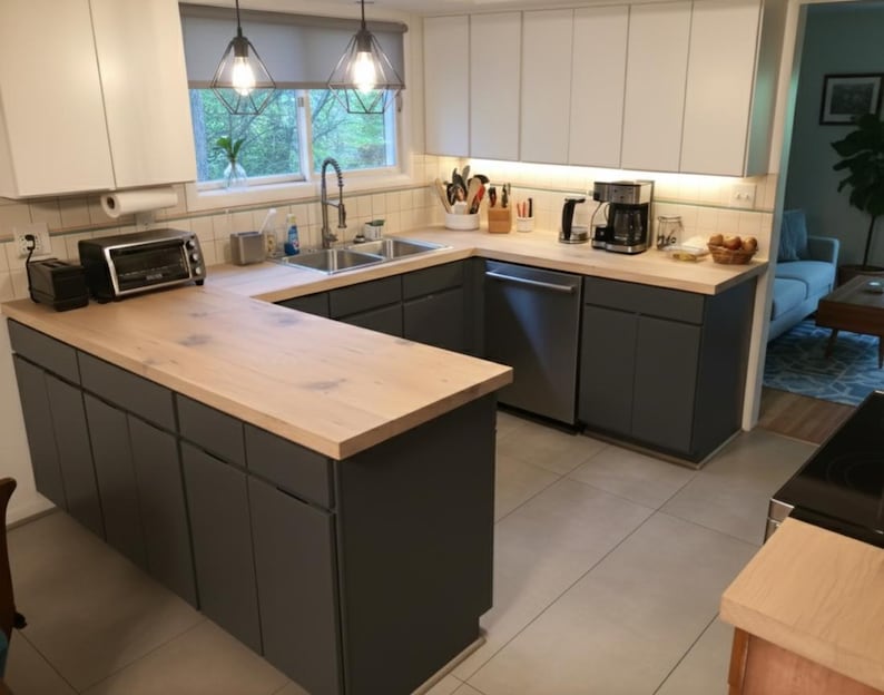 K&ouml;nnte beinhalten: Eine moderne K&uuml;che mit grauen Schr&auml;nken, hellen Holz-Arbeitsplatten und Edelstahlger&auml;ten. Die K&uuml;che hat eine U-f&ouml;rmige Anordnung mit einem Fenster &uuml;ber der Sp&uuml;le und Pendelleuchten.