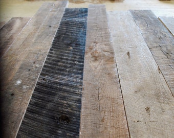 Könnte beinhalten: Nahaufnahme von wiederverwendeten Holzdielen, die die natürliche Maserung und Textur des Holzes zeigen. Die Dielen sind versetzt angeordnet, wobei einige Dielen dunkler sind als andere. Das Holz hat ein rustikales und verwittertes Aussehen.