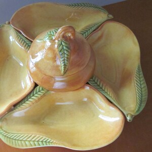 May include: A ceramic serving dish set with a central lidded bowl and five pear-shaped dishes. The set is yellow with green leaf accents and a glossy finish. Ideal for serving fruit or snacks.