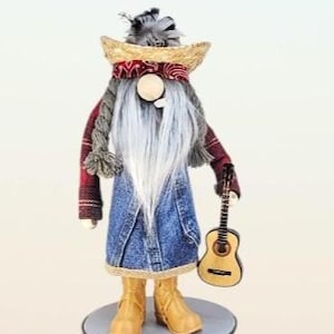 May include: A whimsical gnome figurine dressed in denim overalls, a red plaid shirt, and a straw hat. The gnome has a long white beard and holds a small wooden guitar. It stands on a gray platform and wears tan boots.