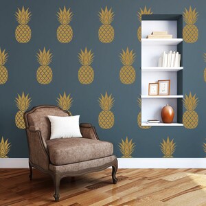 May include: A blue wall with a white shelf unit and a brown armchair. The wall is decorated with a repeating pattern of gold pineapple silhouettes.