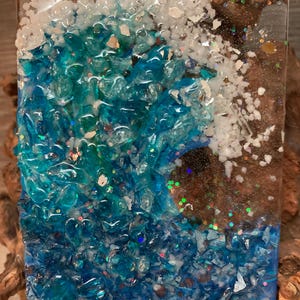May include: A blue and white night light with a wave design made from crushed glass and glitter.