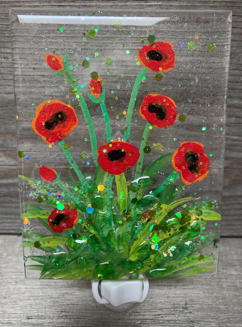Peut inclure: Un veilleuse en verre teint&eacute; repr&eacute;sentant un motif de coquelicot rouge avec des feuilles vertes et des accents de paillettes dor&eacute;es.