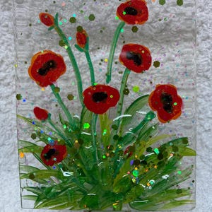 Peut inclure: Une veilleuse en verre avec une image peinte de coquelicots rouges et de feuillage vert. Le verre est d&eacute;cor&eacute; de paillettes iris&eacute;es.