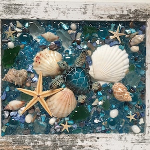 May include: A framed mosaic art piece featuring a sea turtle, seashells, and starfish on a blue background with glass pieces.