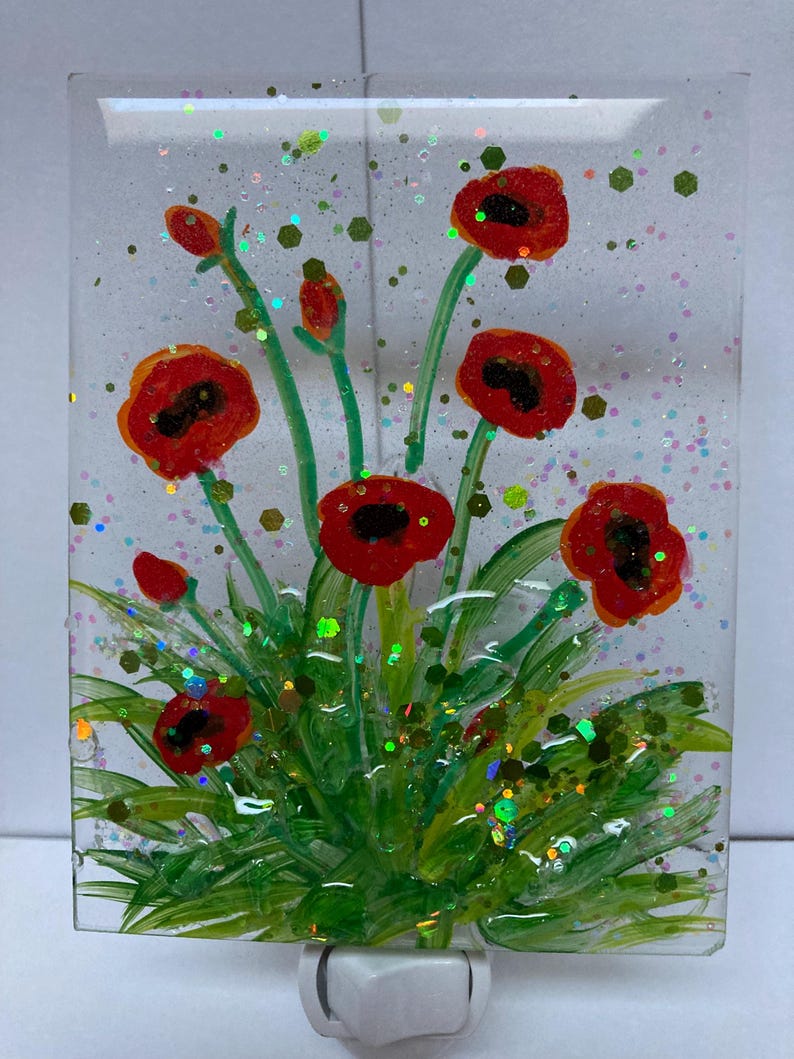 Peut inclure: Une veilleuse en verre avec une image peinte de coquelicots rouges et de feuilles vertes. Le verre est recouvert de paillettes iris&eacute;es.