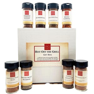 Pu&ograve; includere: Una scatola regalo bianca con la scritta "Hot Off The Grill Gift Box" sul davanti. La scatola contiene otto barattoli di vetro di spezie con etichette rosse e bianche. Le etichette riportano il testo "Spice Shop" e i nomi delle spezie, come "Sweetgrass Prairie Blend" e "Cowboy Steak Rub".