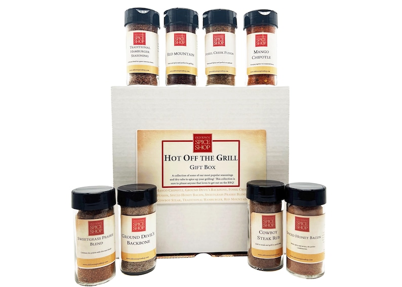 Pu&ograve; includere: Una scatola regalo bianca con la scritta "Hot Off The Grill Gift Box" sul davanti. La scatola contiene otto barattoli di vetro di spezie con etichette rosse e bianche. Le etichette riportano il testo "Spice Shop" e i nomi delle spezie, come "Sweetgrass Prairie Blend" e "Cowboy Steak Rub".