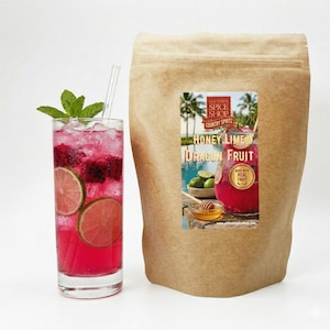 May include: A tall glass of pink dragon fruit cocktail with lime slices and mint, next to a brown paper bag with a label that reads "Honey Lime Dragon Fruit". The drink is a refreshing beverage.