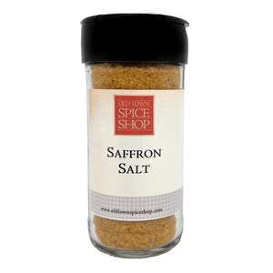 May include: A clear glass spice jar with a black plastic lid containing golden-brown saffron salt. The white label features a red square logo with the text OLD TOWN SPICE SHOP, the words SAFFRON SALT, and the website www.oldtownspiceshop.com.