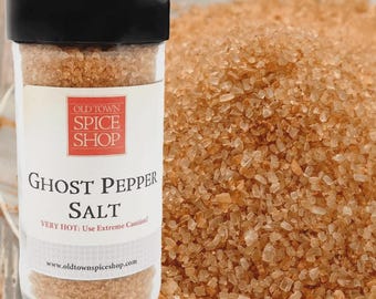 May include: A clear plastic spice jar with a black lid containing coarse, light brown ghost pepper salt. The white label features the red Old Town Spice Shop logo, the text Ghost Pepper Salt, and the warning Very Hot: Use Extreme Caution.
