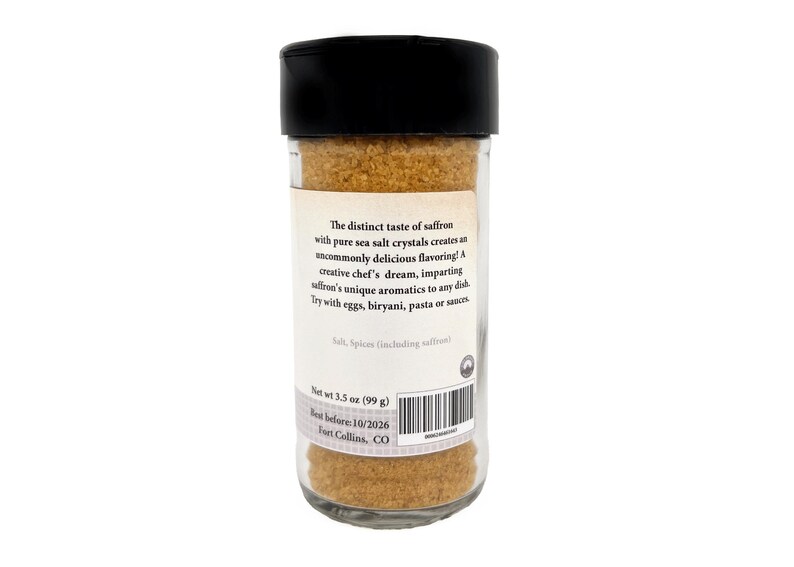 May include: A clear glass spice jar with a black plastic lid, filled with golden-brown saffron sea salt. The label reads: The distinct taste of saffron with pure sea salt crystals creates an uncommonly delicious flavoring! Net wt 3.5 oz (99 g).