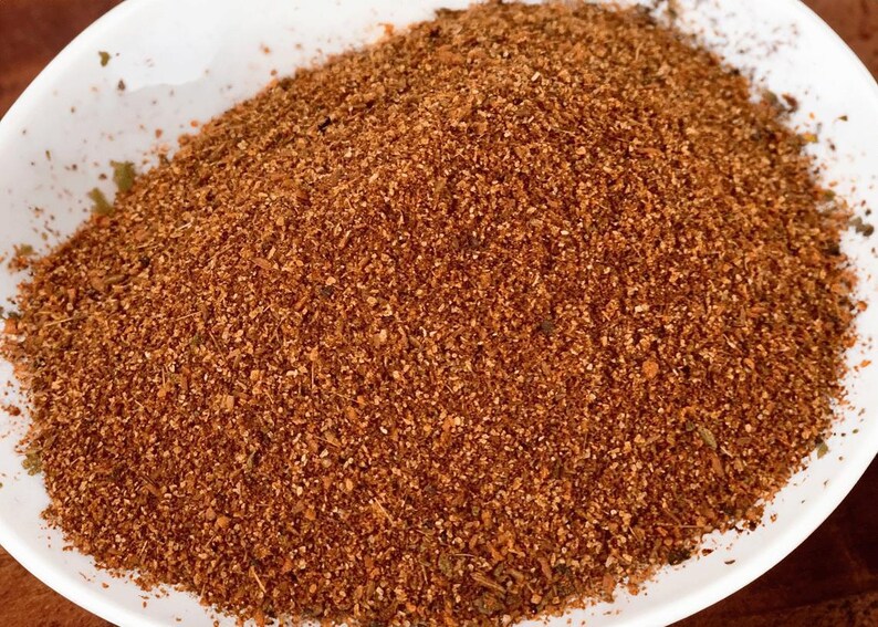 Pu&ograve; includere: Primo piano di un mix di spezie marroni in una ciotola bianca. Il mix di spezie &egrave; composto da piccole particelle finemente macinate.
