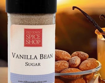 Könnte beinhalten: Ein durchsichtiges Gewürzglas aus Glas mit schwarzem Deckel, gefüllt mit beigefarbenem Vanillezucker. Das weiße Etikett zeigt ein rotes quadratisches Logo mit dem Text OLD TOWN SPICE SHOP, VANILLA BEAN SUGAR und die Website www.oldtownspiceshop.com.