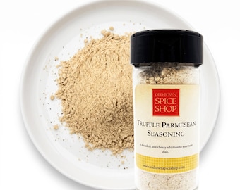 May include: A clear plastic spice jar with a black lid containing Truffle Parmesan Seasoning from Old Town Spice Shop, positioned next to a white plate holding a pile of the light beige, finely ground seasoning powder.