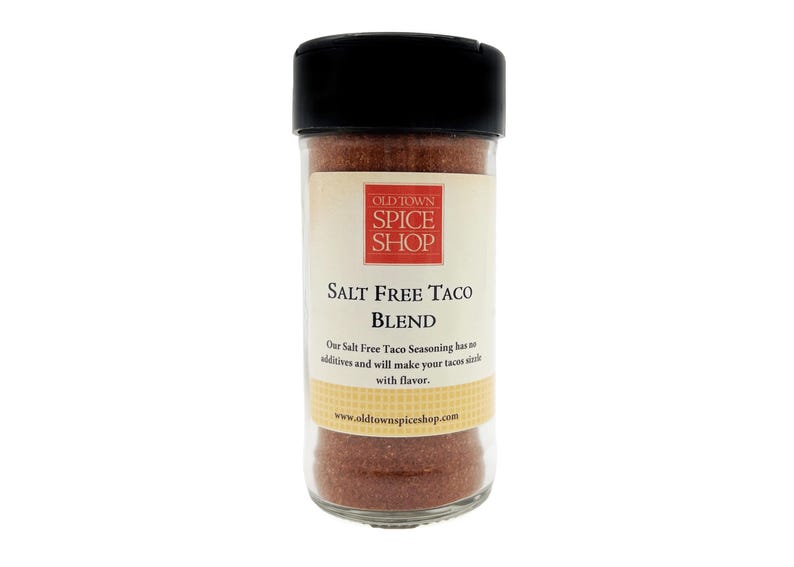 Pu&ograve; includere: Un barattolo di vetro di condimento Old Town Spice Shop Salt Free Taco Blend. Il barattolo ha un coperchio nero e un'etichetta bianca con testo rosso che dice "Old Town Spice Shop Salt Free Taco Blend". L'etichetta include anche il testo "Our Salt Free Taco Seasoning has no additives and will make your tacos sizzle with flavor." e "www.oldtownspiceshop.com".
