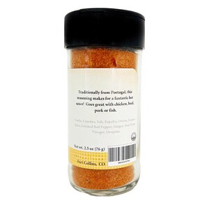 May include: A clear glass spice jar with a black lid, filled with a reddish-orange seasoning blend. The label reads "Traditionally from Portugal" and lists ingredients. Net weight is 2.5 oz (76 g).
