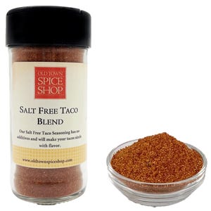 Pu&ograve; includere: Un barattolo di vetro di miscela di condimento per tacos senza sale con un'etichetta marrone che recita "Old Town Spice Shop Salt Free Taco Blend". L'etichetta include anche l'indirizzo del sito web "www.oldtownspiceshop.com". Una piccola ciotola di condimento &egrave; mostrata accanto al barattolo.