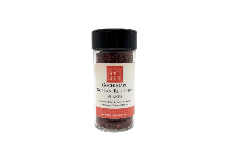 May include: A glass jar of red Korean Gochugaru chili flakes. The jar has a black lid and a white label with the text "Old World Spice Shop" and "Gochugaru Korean, Red Chili Flakes".