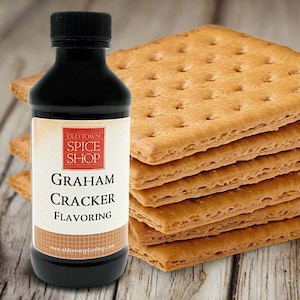 May include: A black bottle of "Graham Cracker Flavoring" from Old Town Spice Shop, next to a stack of graham crackers. The label is white with red text and a brown border. The crackers are golden brown and square with perforations.